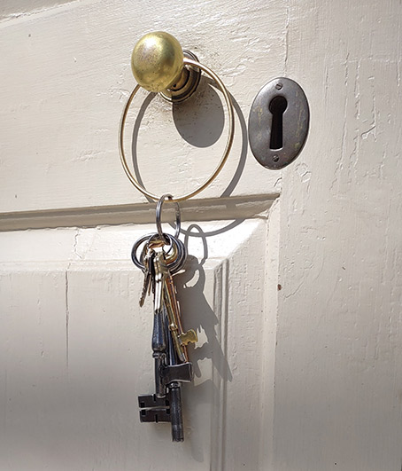 An old set of keys on a large ring hanging from the door knob of an old wooden door to the historic Wren Building